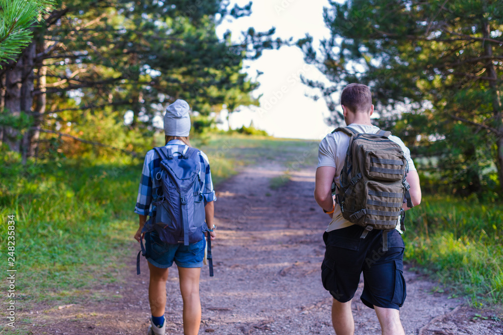 Obraz premium Young couple walking in the forest. Hiking concept in the mountain in summer