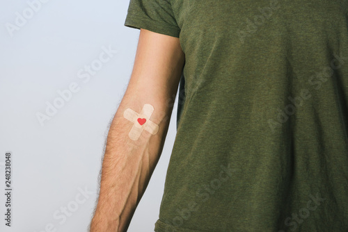 Foto Partial view of patient in green t-shirt with plasters on grey background, blood