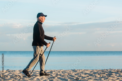 Obraz na płótnie Nordic walking - senior man working out on beach. Healthy lifestyle w salonie