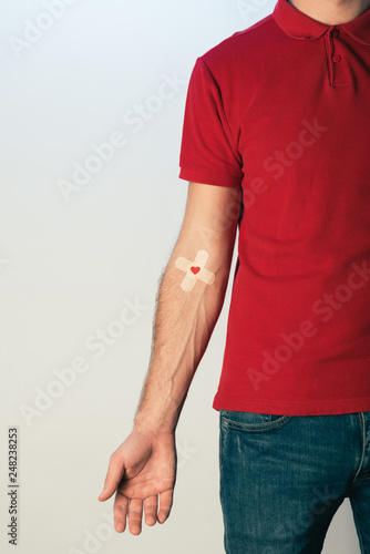 Billede på lærred Partial view of patient in red t-shirt with plasters, blood donation concept