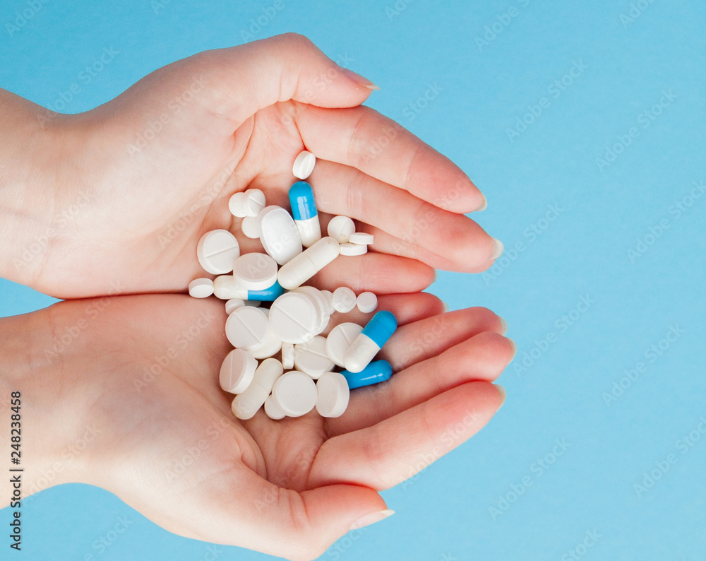 Woman's holding cupped hand full of pills, view from above