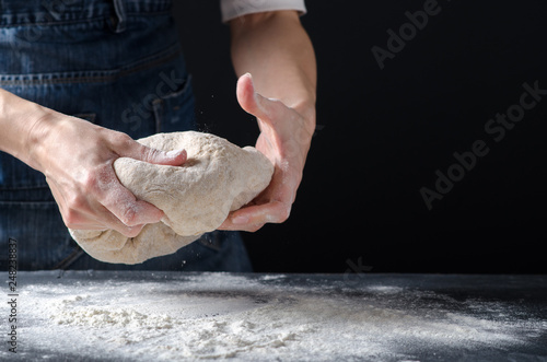 Woman kneading dough on sprinkled with flour table. Yeast dough for bread, rolls, pizza, focaccia or pie. Homemade dough. Design for text.