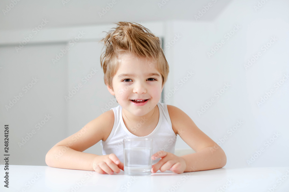 Cute smiling boy with glass of water isolated on a white background