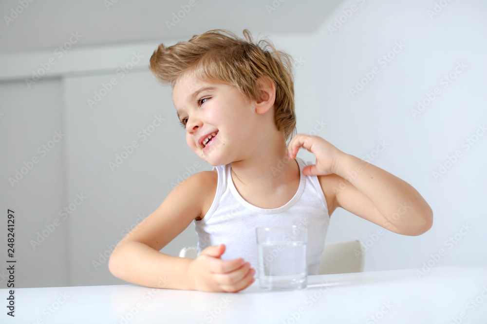 Cute smiling boy with glass of water isolated on a white background Cute smiling boy with glass of water isolated on a white background