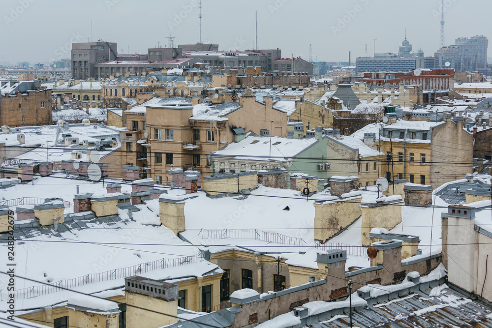 Panoramic photo of the roofs of buildings covered with snow and ice, ice blocks hanging from the eaves of buildings, very snowy winter, city is shrouded in wires, historic city center, winter concept.