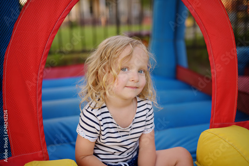 Curly little girl having fun in leisure center for kids. Child sport activity on outdoor playground. Toddler girl playing in kindergarten or entertainment centre.