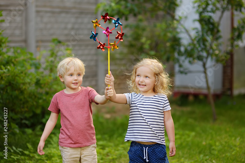 Little boy and girl having fun during walk. Happy child with pinwheel.