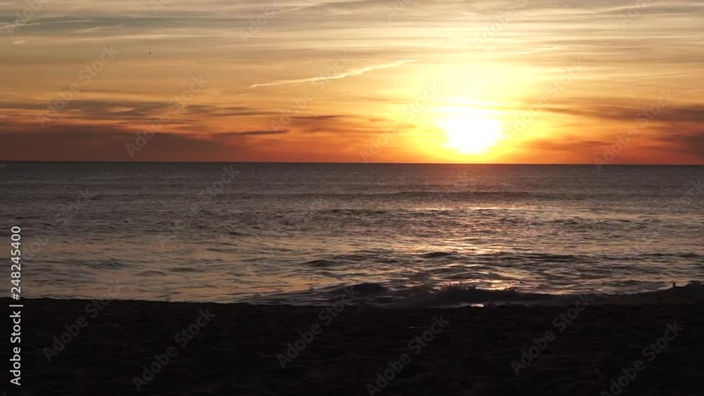 Sunset at beach in Faro Algarve, Portugal with dramatic orange sky and reflections on waves Sunset at beach in Faro Algarve, Portugal with dramatic orange sky and reflections on waves