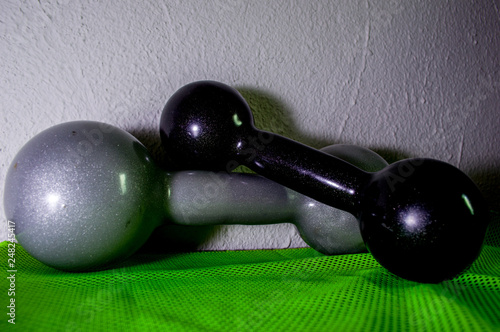 gray and black dumbbells for the practice of bodybuilding exercises, in gray color, and a sport towel