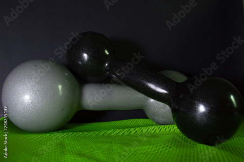 gray and black dumbbells for the practice of bodybuilding exercises, in gray color, and a sport towel