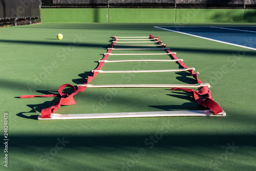 Agility ladder lying on tennis court waiting for next player to improve the footwork skills. photo