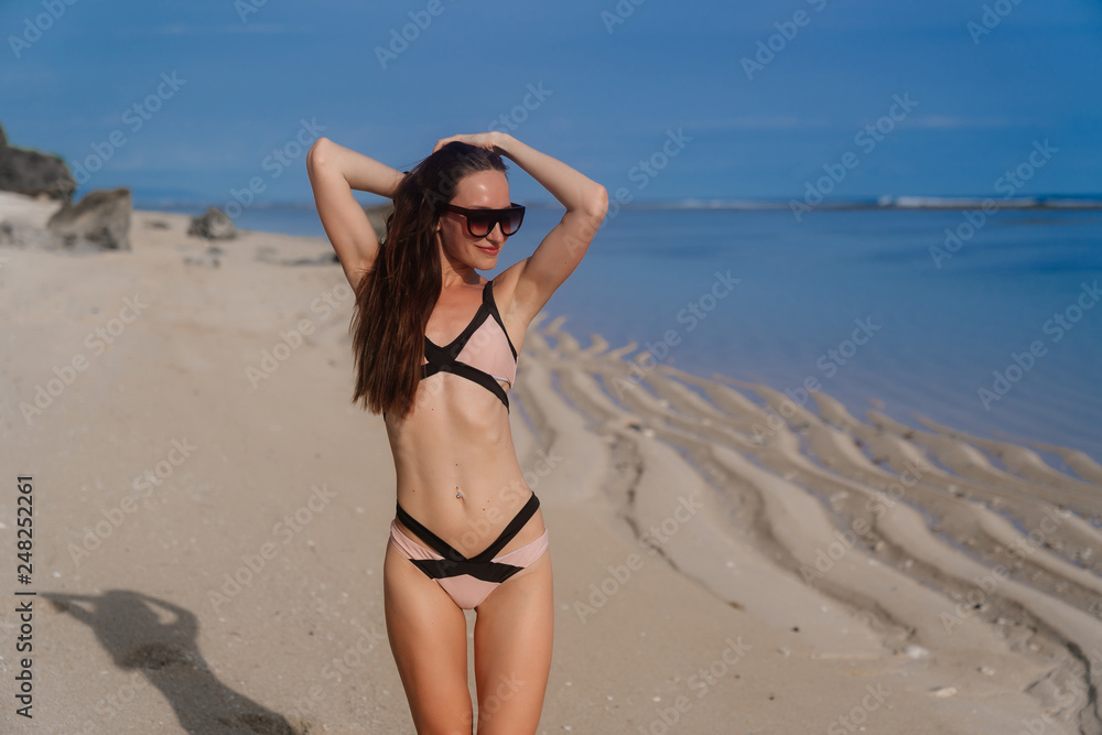 Sexy girl in swimsuit with sunglasses posing on sandy beach Sexy girl in swimsuit with sunglasses posing on sandy beach