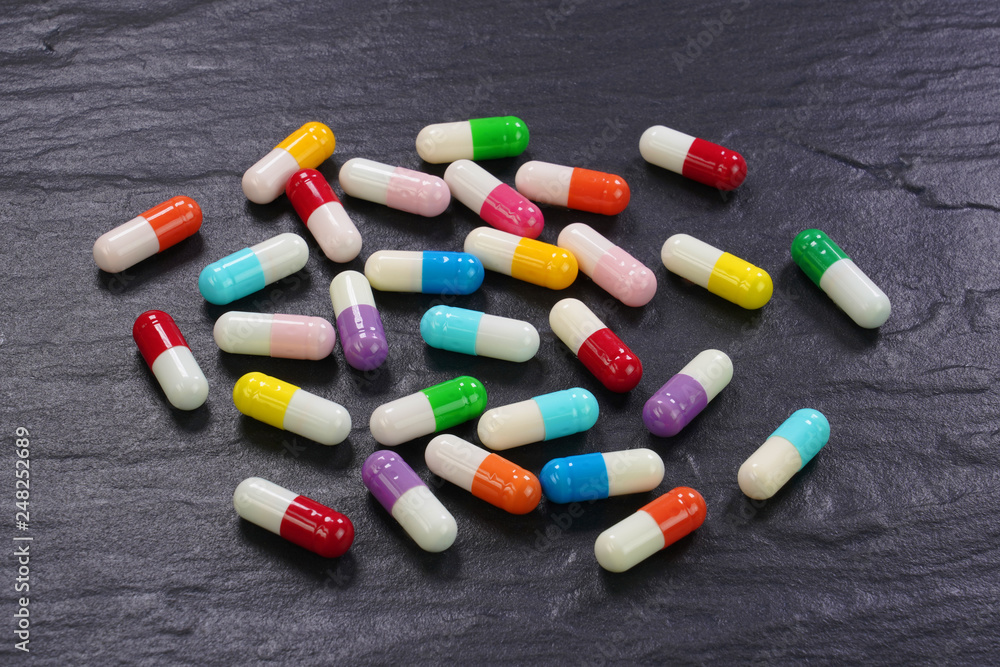  Colorful medical capsules on black background .
