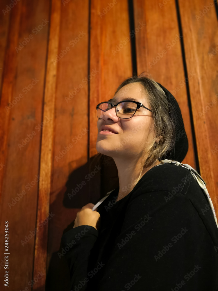 Obraz premium Young Hispanic girl with confident expression and cool attitude, with good style black clothes. Wood background.