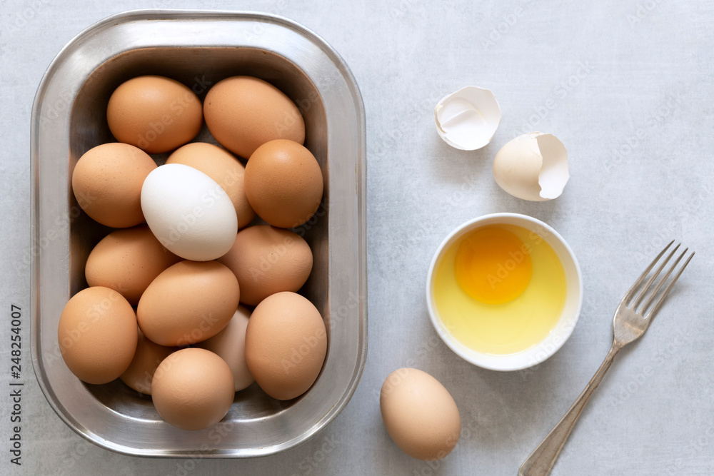 Eggs in a dish with a cracked egg in a bowl. Eggs in a dish with a cracked egg in a bowl.