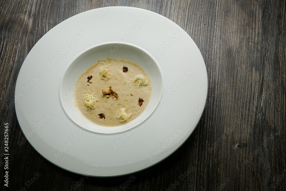 beige seafood cream soup decorated with dried squid and soy sauce beige seafood cream soup decorated with dried squid and soy sauce