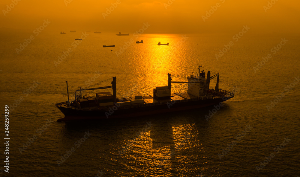 silhouette shipping cargo containers on the sea and the sunrise background