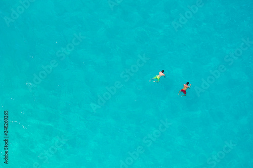 BALI, INDONESIA - 3rd FEB 2019; Aerial view of people swimming in the transparent turquoise sea over sunny day at Kelingking beach. Top view from cliff.