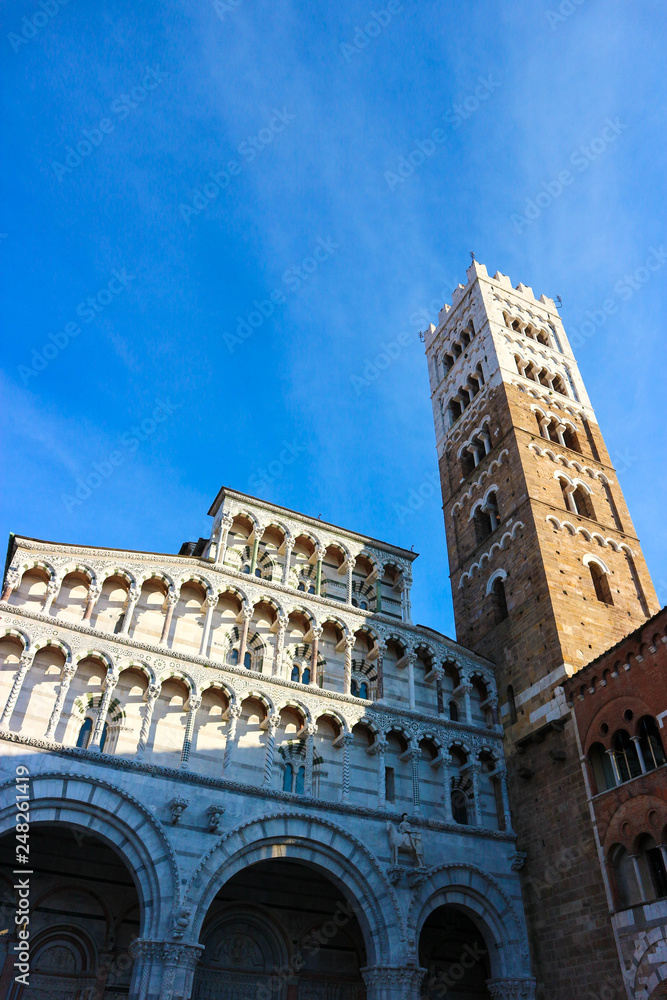 Facade and bell tower of Lucca Cathedral of Saint Martin with blue winter sky on background, Tuscany, Italy