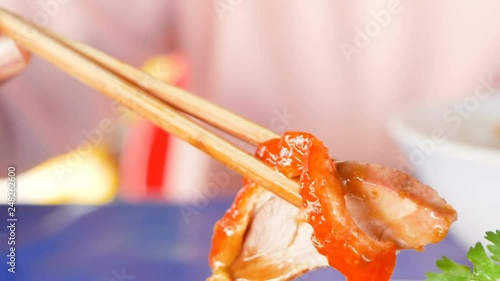 hand using chopsticks with roasted duck