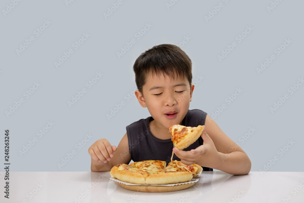 Cute boy eating pizza isolated on blue background Cute boy eating pizza isolated on blue background