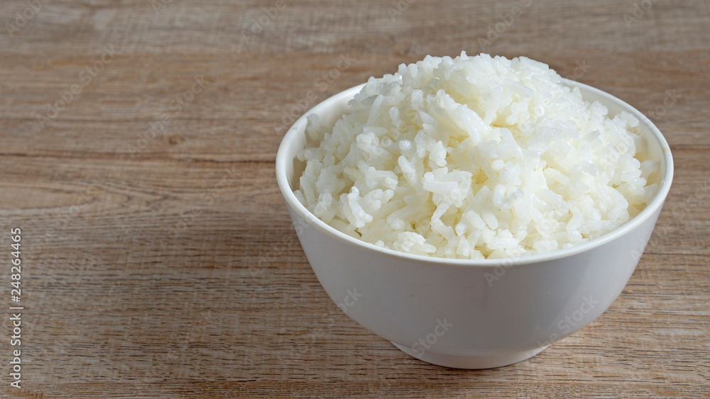 Cooked jasmine rice in white bowl on wooden table with copy space,high calories food,selective focus Cooked jasmine rice in white bowl on wooden table with copy space,high calories food,selective focus