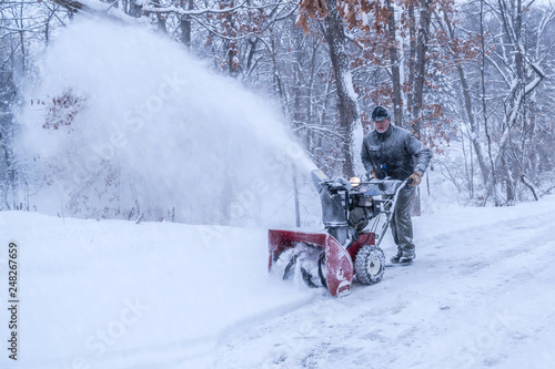 Foto An old white man is using snow blower to plow / blow snow