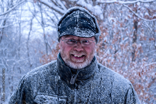 A portait of an old Caucasian man smiling in snow shower