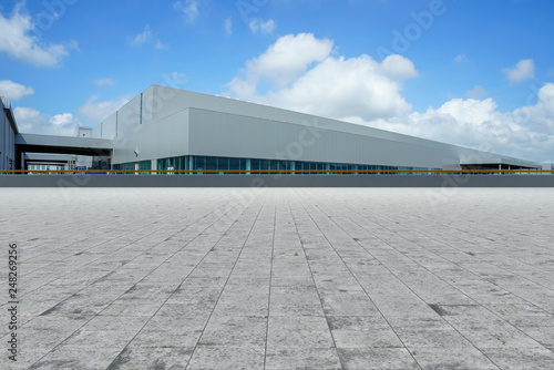 Empty square floor tiles and modern factory buildings and warehouses..