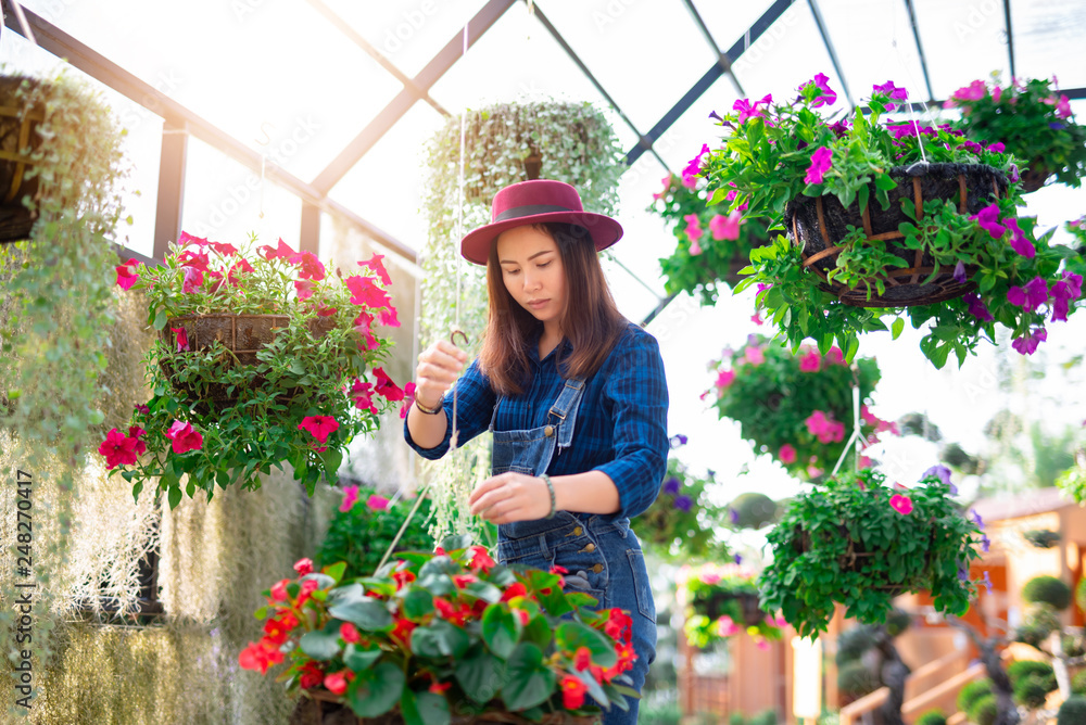 Young women and flower care in the garden that are blooming in the morning