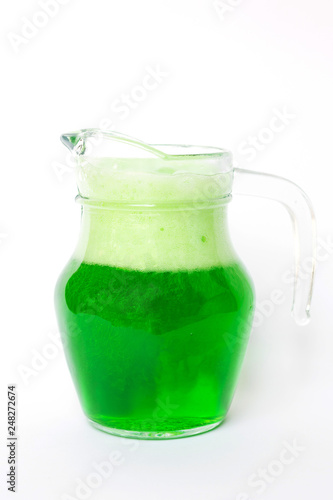 Glass jug of soft drink green soda with dancing bubbles isolated on white background