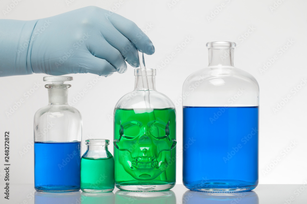 A hand in laboratory gloves mixes chemistry. Liquid in laboratory bottles. Scientific biochemical laboratory. Colorful liquid. A hand in laboratory gloves mixes chemistry. Liquid in laboratory bottles. Scientific biochemical laboratory. Colorful liquid.
