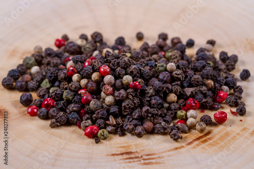Black, white and red pepper peas on a wooden background
