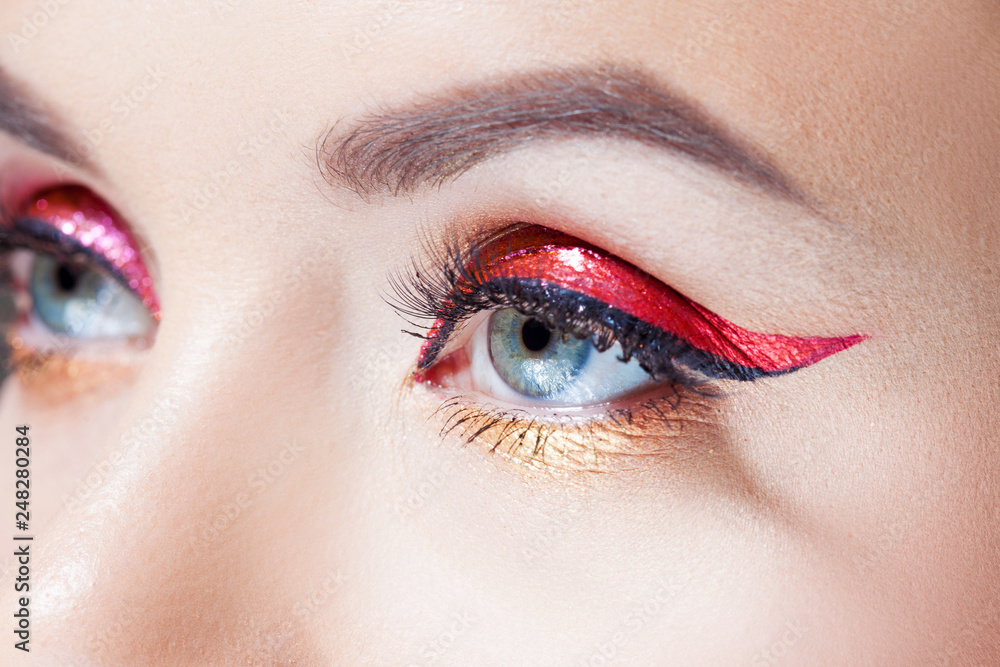 Amazing Bright eye makeup in luxurious red arrow. Red and gold shining tones, eye shadow.