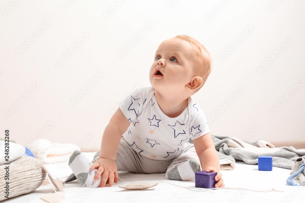 Little boy in cute clothes sitting on floor against light background. Baby accessories Little boy in cute clothes sitting on floor against light background. Baby accessories