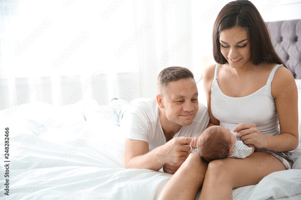 Happy couple with their newborn baby on bed. Space for text Happy couple with their newborn baby on bed. Space for text