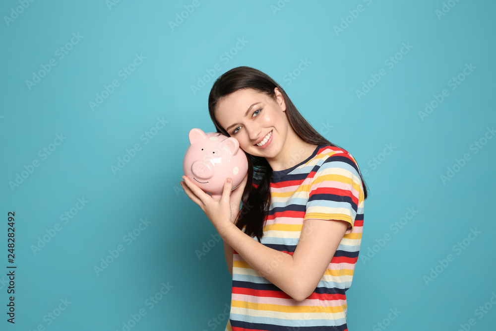 Young woman with piggy bank on color background Young woman with piggy bank on color background