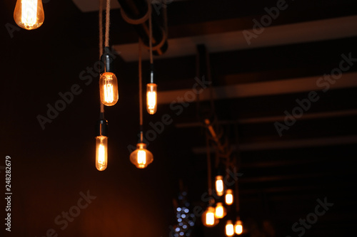 Glowing lamp bulbs in dark room. Space for text