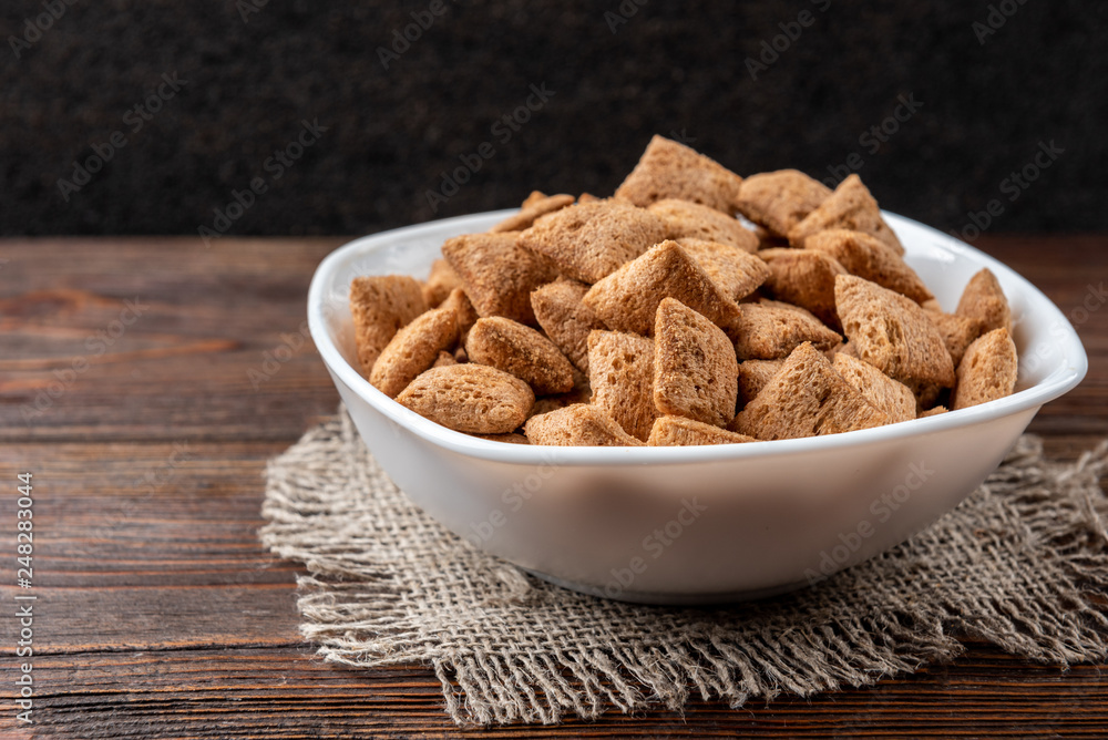 Dried breakfast pads in white bowl on dark wooden background. Dried breakfast pads in white bowl on dark wooden background.