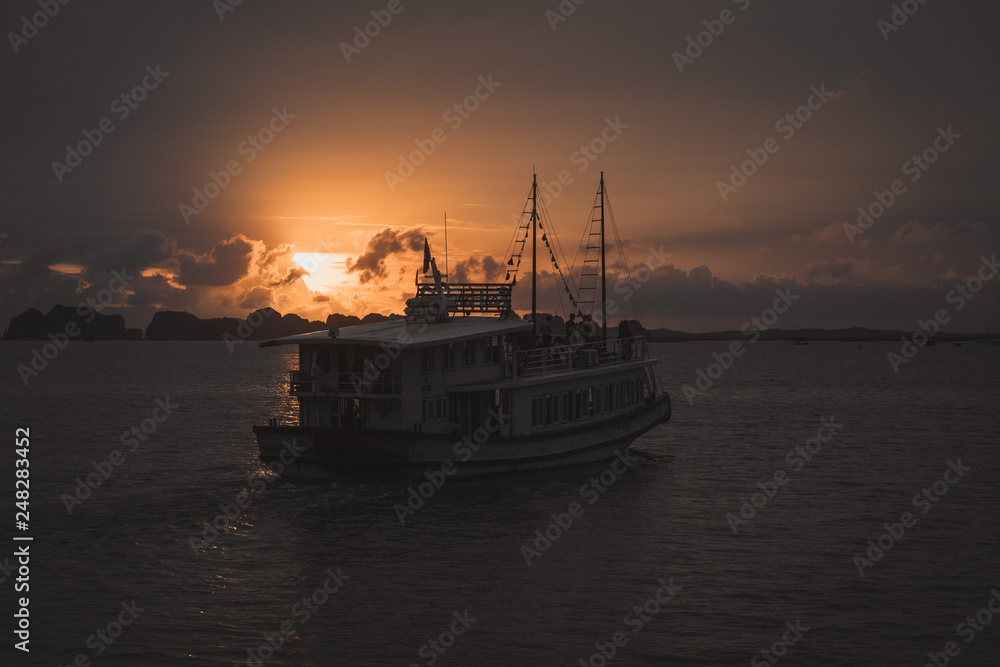 Boat sailing in Ha Long bay Vietnam at sunset Boat sailing in Ha Long bay Vietnam at sunset
