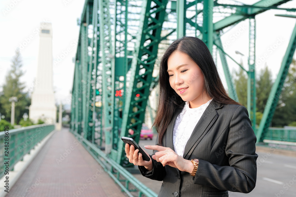Fototapeta premium Asian woman smile and using smartphone for social network,Beautiful Asian woman checking her jobs in smartphone
