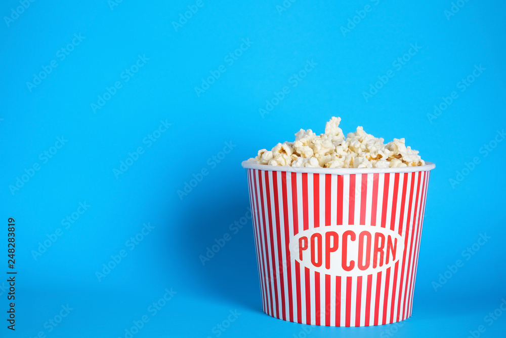 Bucket of fresh tasty popcorn on color background, space for text. Cinema snack