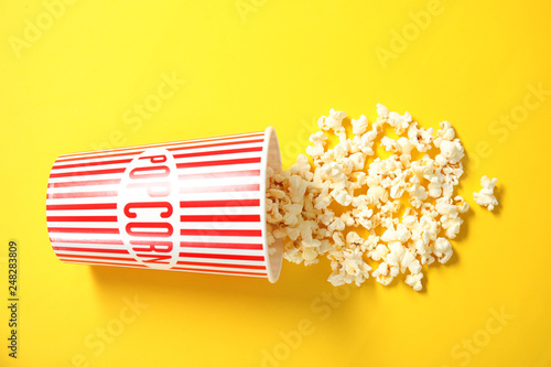 Cup with fresh tasty popcorn on color background, top view. Cinema snack