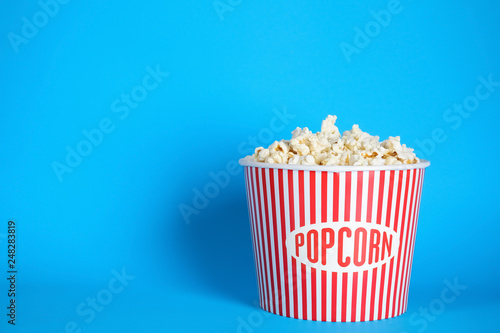 Bucket of fresh tasty popcorn on color background, space for text. Cinema snack
