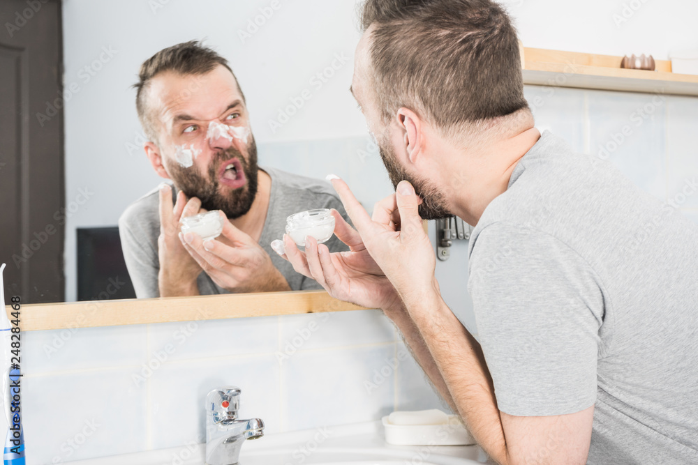 Man applying moisturizer cream in bathroom Man applying moisturizer cream in bathroom