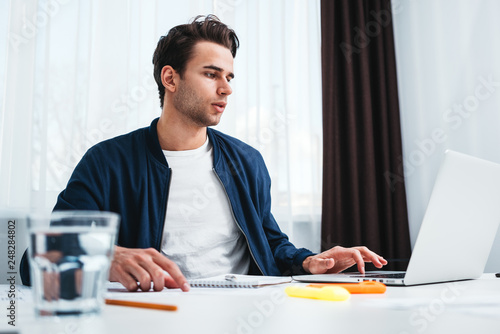 Concentrated manager working on laptop and reading information in modern spale office. Businessman sits at her desk and prepearing project photo