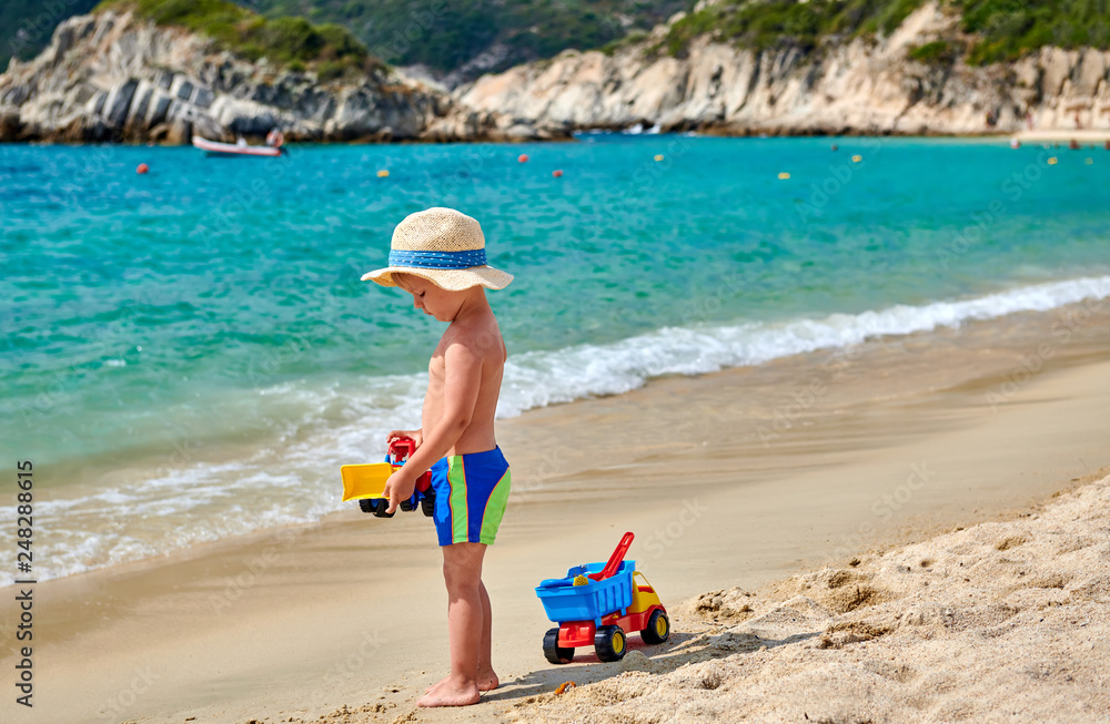 Toddler boy on beach with toys Toddler boy on beach with toys