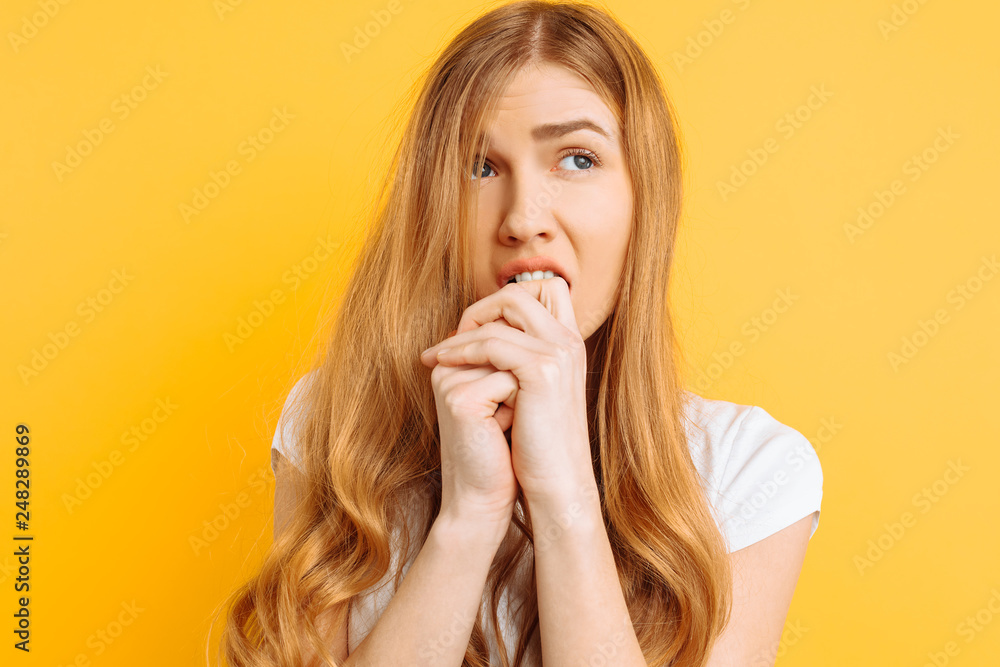 beautiful young girl is worried, a woman with a terrified face, on a yellow background beautiful young girl is worried, a woman with a terrified face, on a yellow background