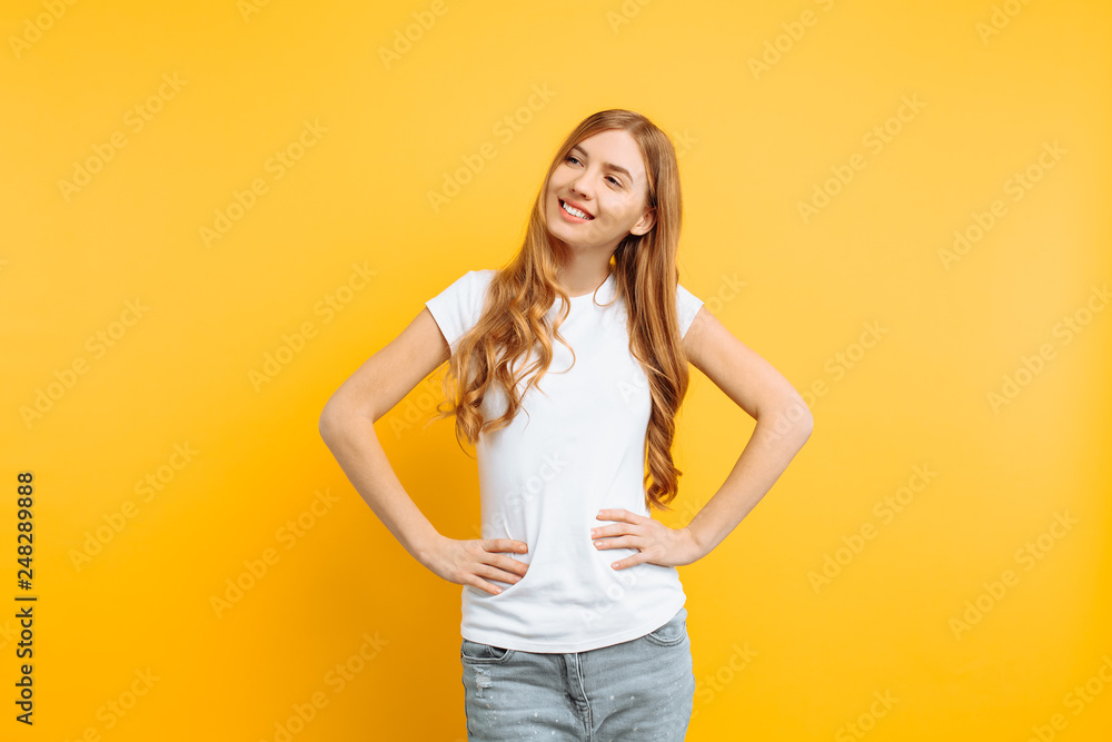 beautiful girl holding hands on waist, portrait of young woman in white t-shirt on yellow background beautiful girl holding hands on waist, portrait of young woman in white t-shirt on yellow background