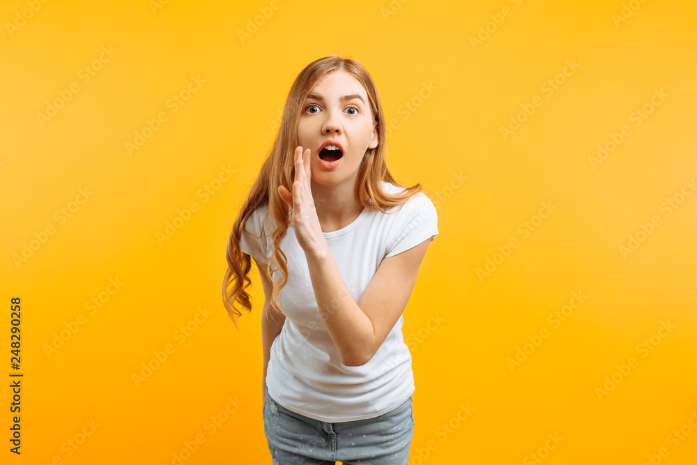 Φωτογραφία shocked woman in white t-shirt, holding a hand near the mouth and telling a secr